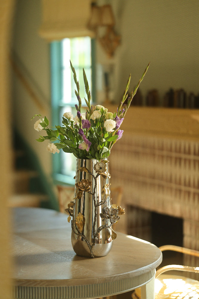 Decorative vase with flowers on a table in a room with a lamp and window.